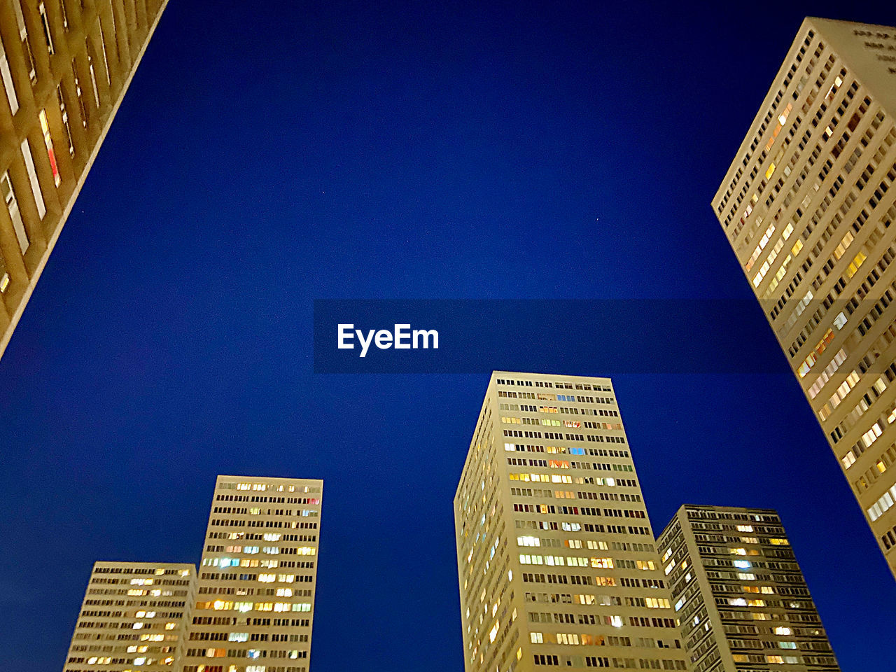 Low angle view of illuminated buildings against clear blue sky