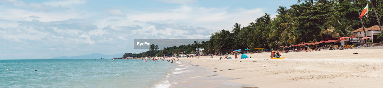 Panoramic view of people on beach against sky