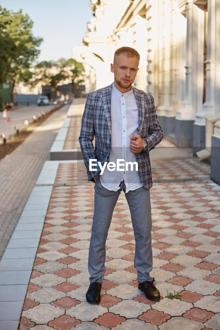 Portrait of young man standing on footpath