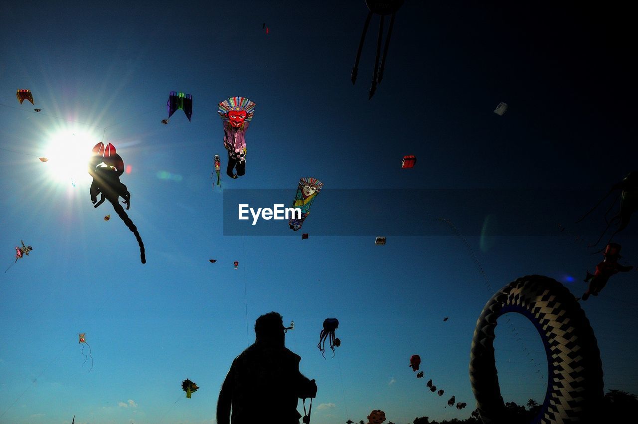 Low angle view of man against kites in sky