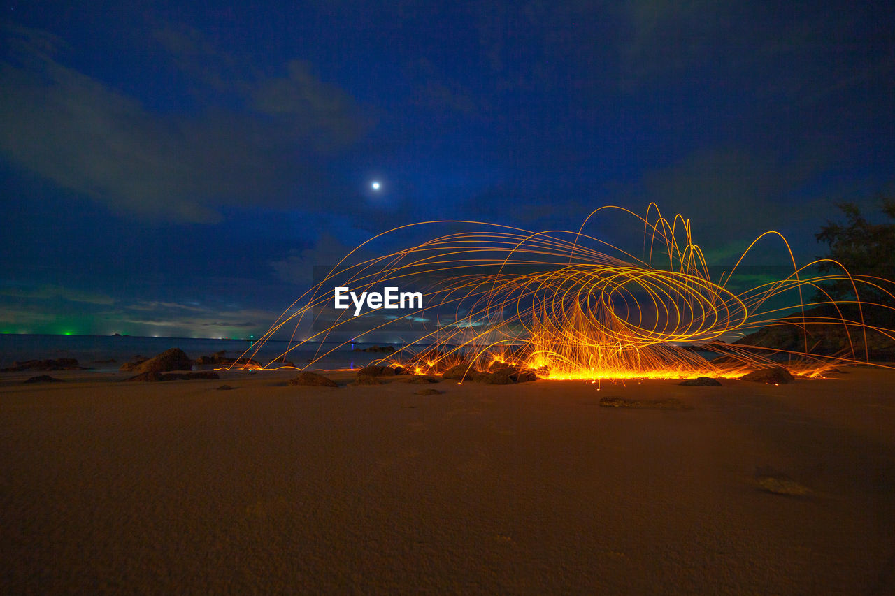 LIGHT TRAILS ON BEACH AGAINST SKY