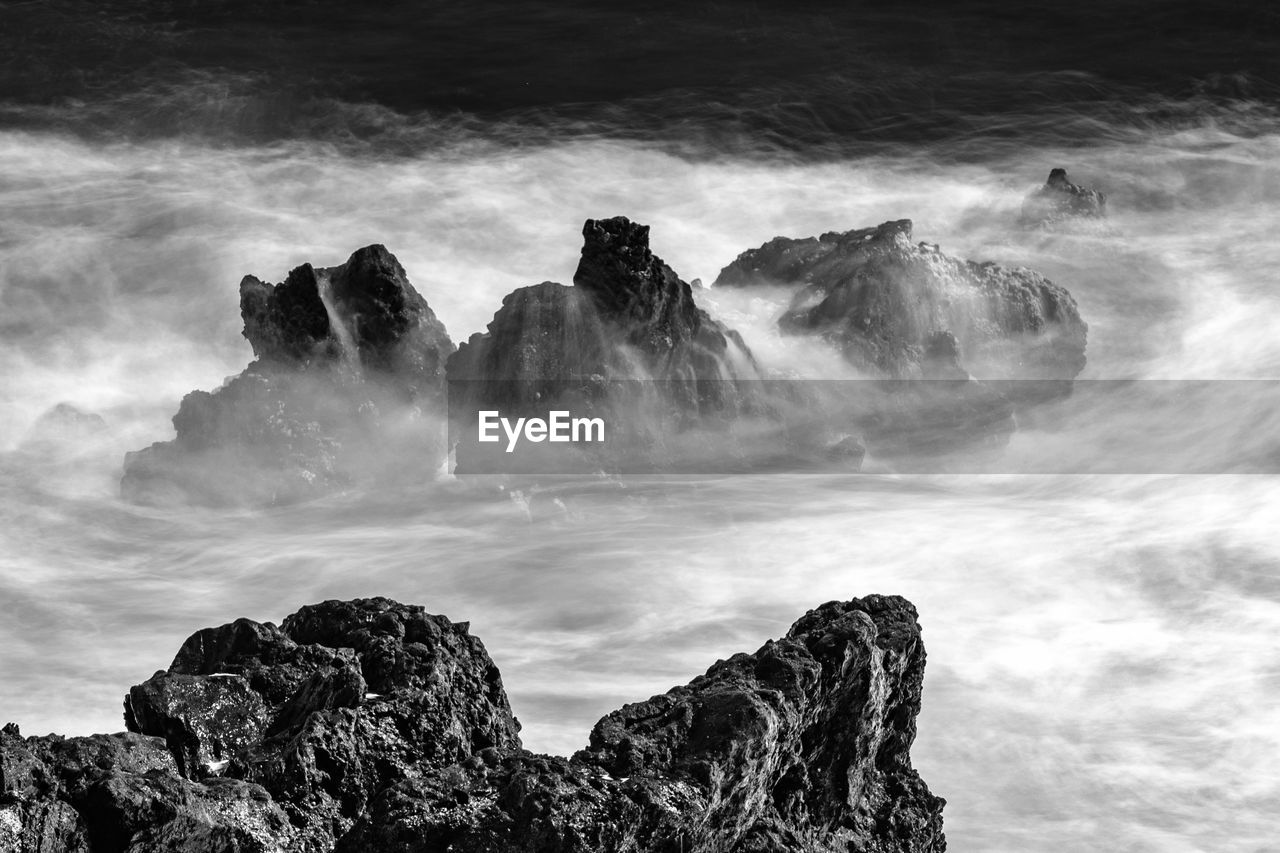 Scenic view of rocks in sea against sky