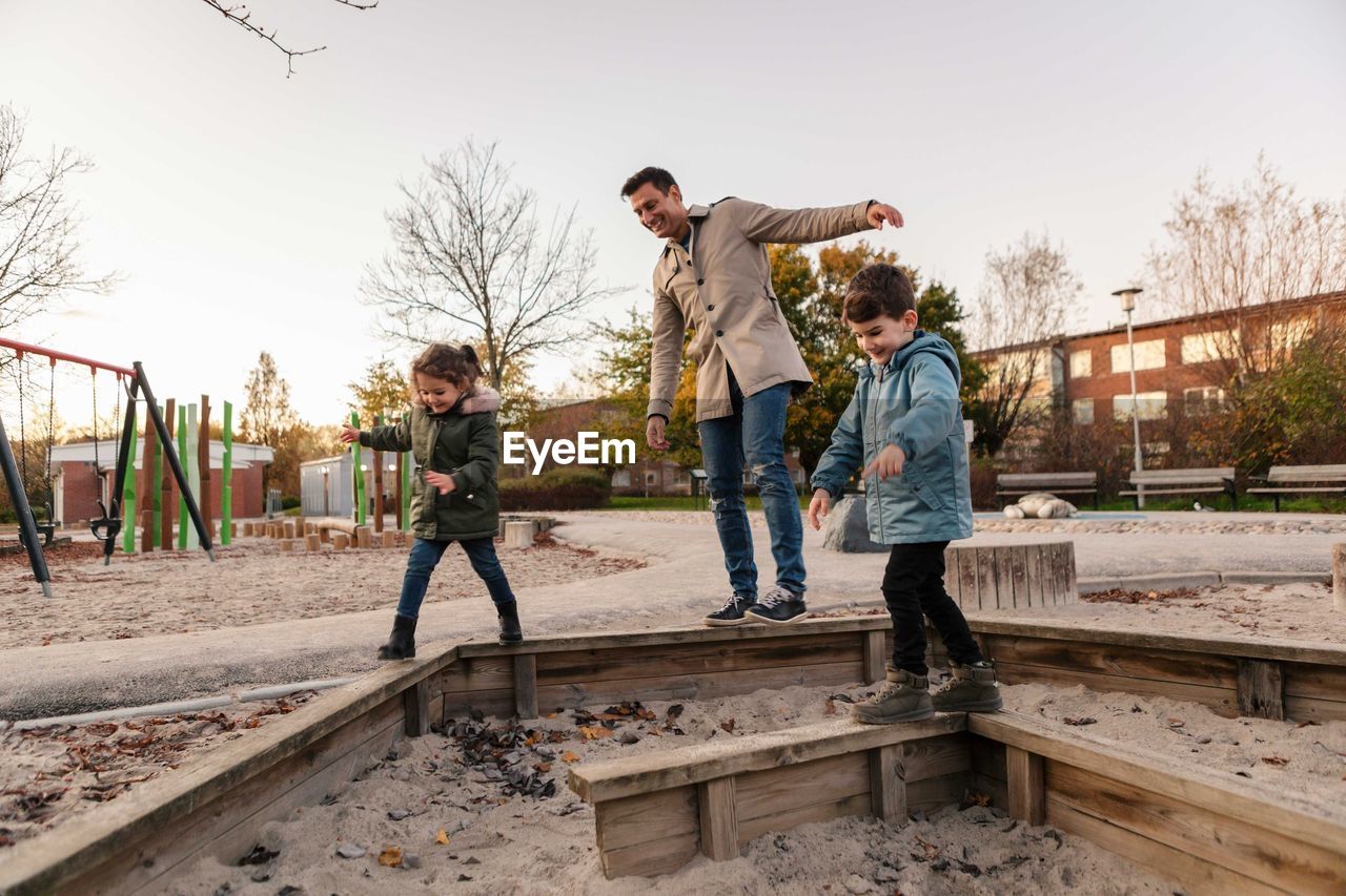 Playful father with children in playground during sunset