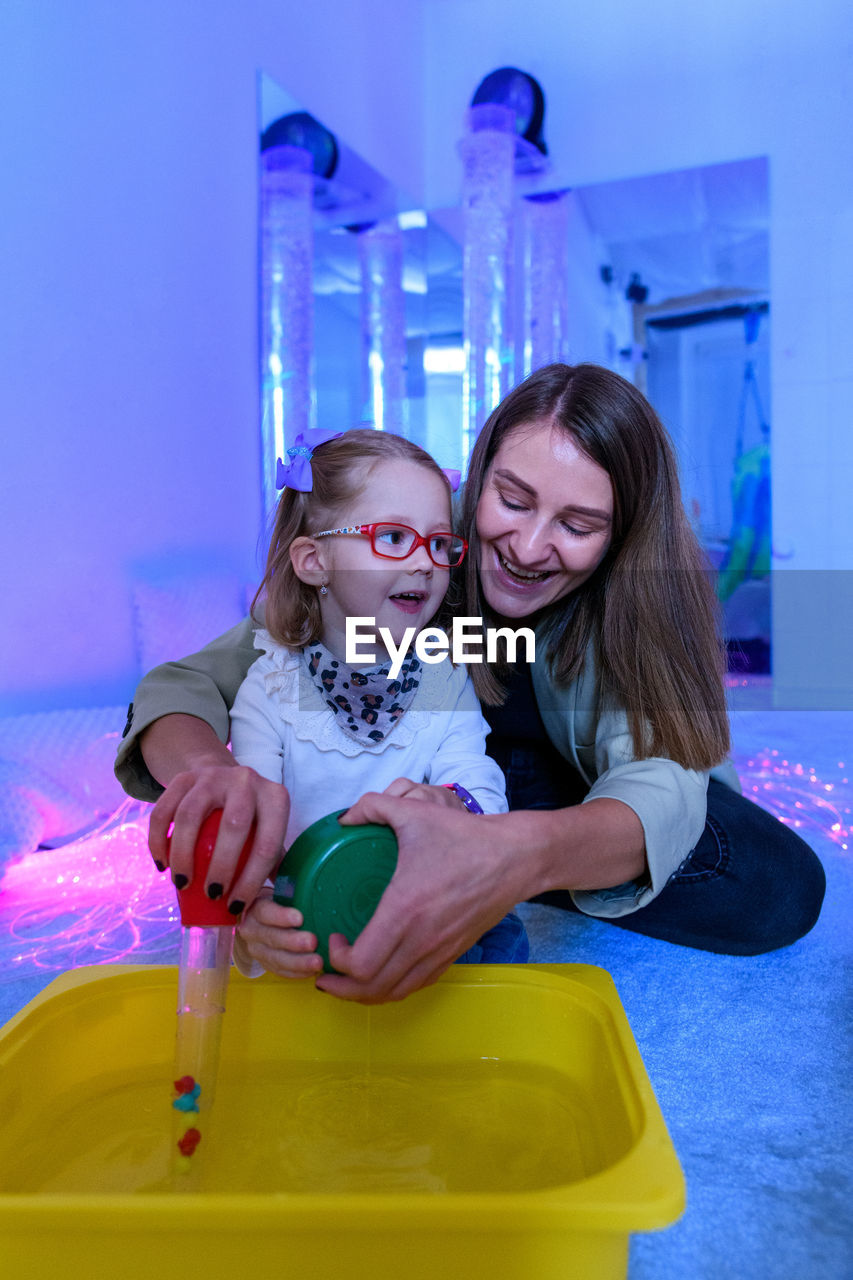 Child living with cerebral palsy interacting with her therapist during therapy session.