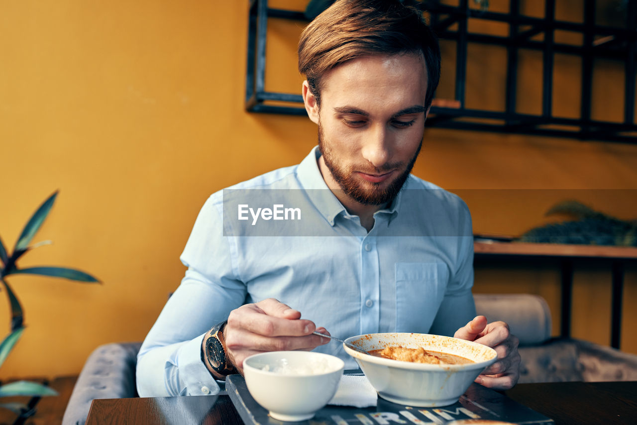 Young man eating food at restaurant