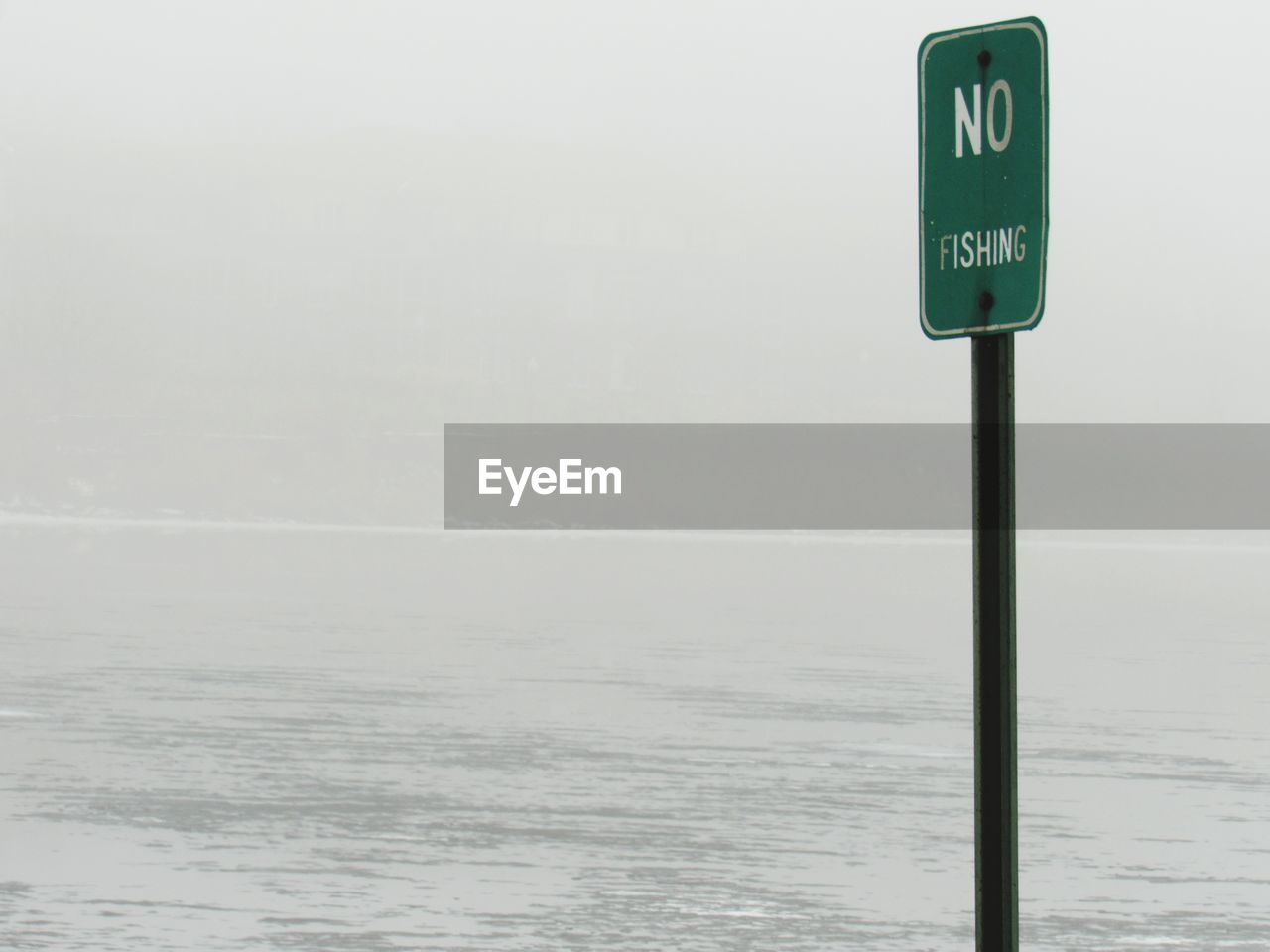 Information sign by sea against sky