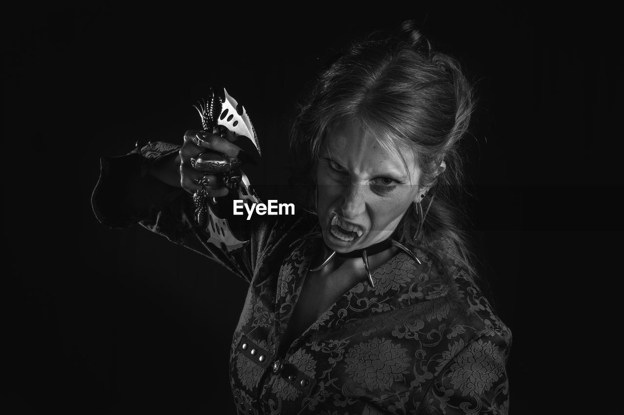 Portrait of spooky woman standing against black background