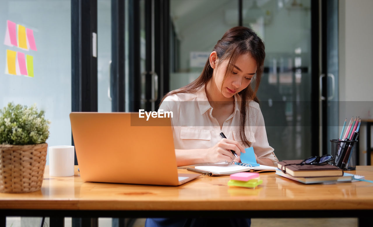 Young woman using mobile phone while sitting on table