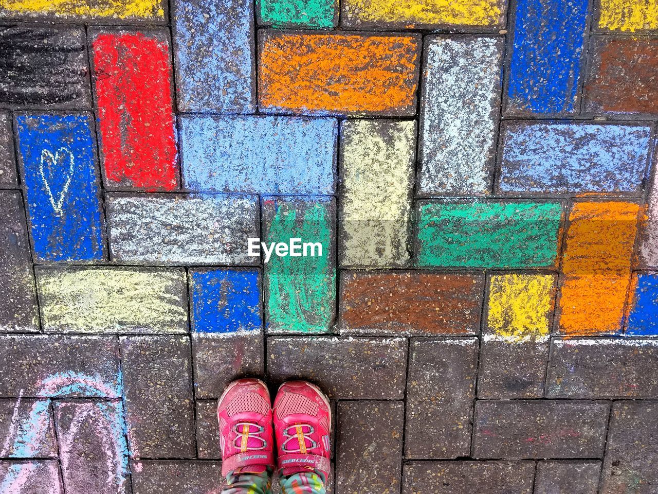 LOW SECTION OF PERSON STANDING ON MULTI COLORED PENCILS