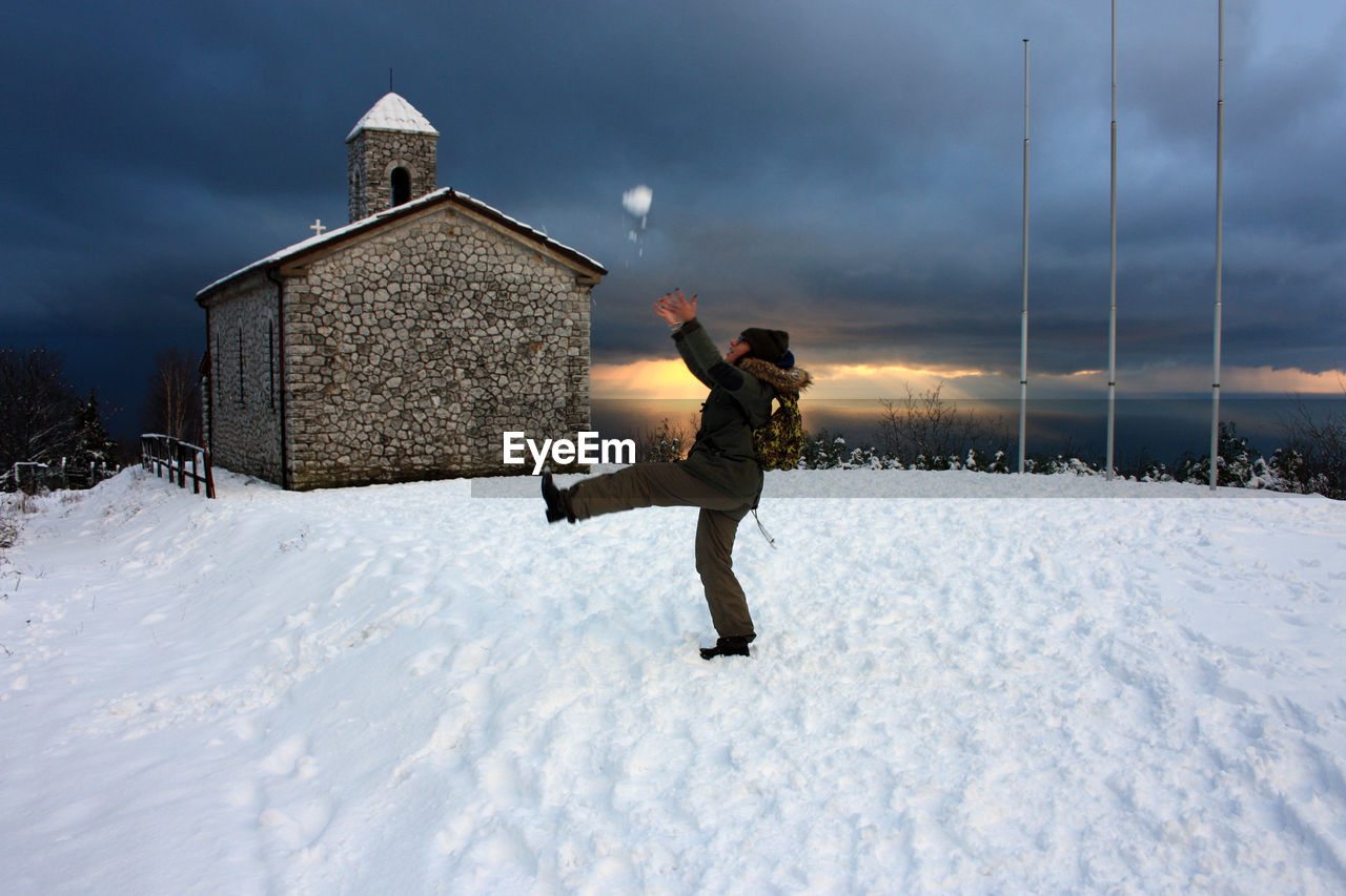 MAN STANDING ON SNOW COVERED FIELD