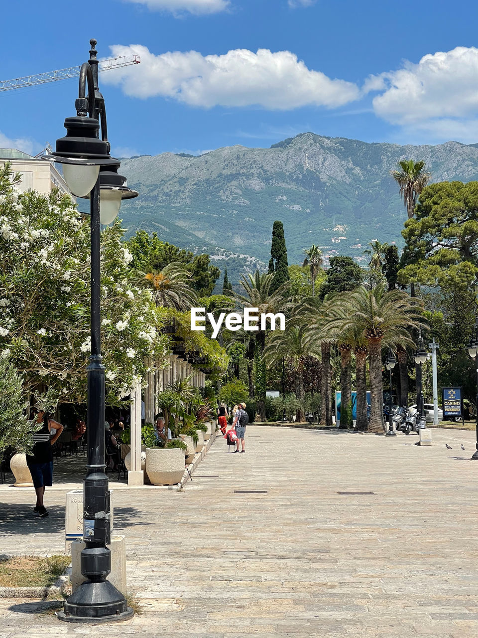 vacation, tree, plant, sky, nature, architecture, street, mountain, town, street light, travel destinations, city, day, walkway, palm tree, cloud, tourism, tropical climate, built structure, travel, outdoors, town square, building exterior, sunlight, footpath, group of people, religion, men, land, beauty in nature