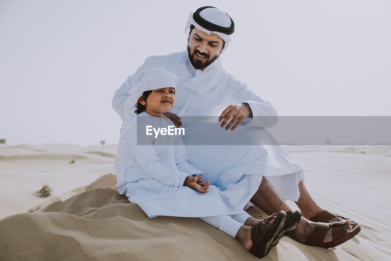 Father and son enjoying while sitting in desert
