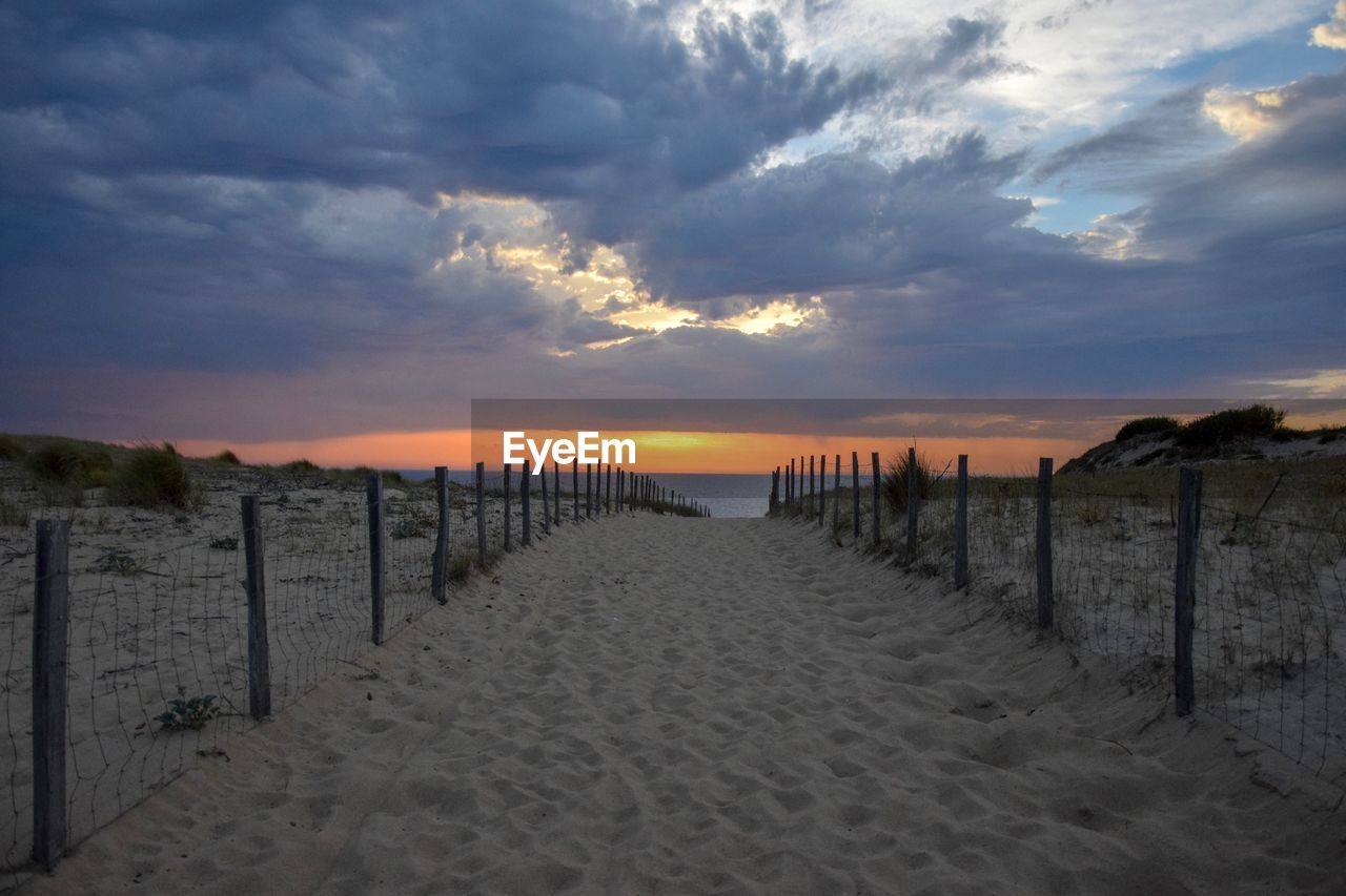 WOODEN POSTS ON BEACH AGAINST SKY