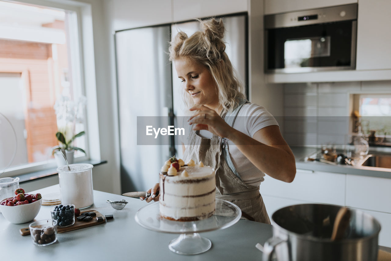 Woman in kitchen decorating cake