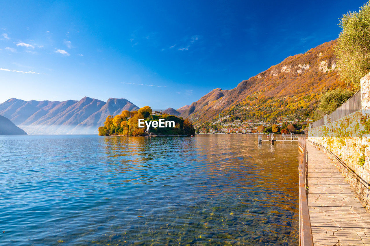 Comacina island, photographed in autumn, with trees, boats and piers around.