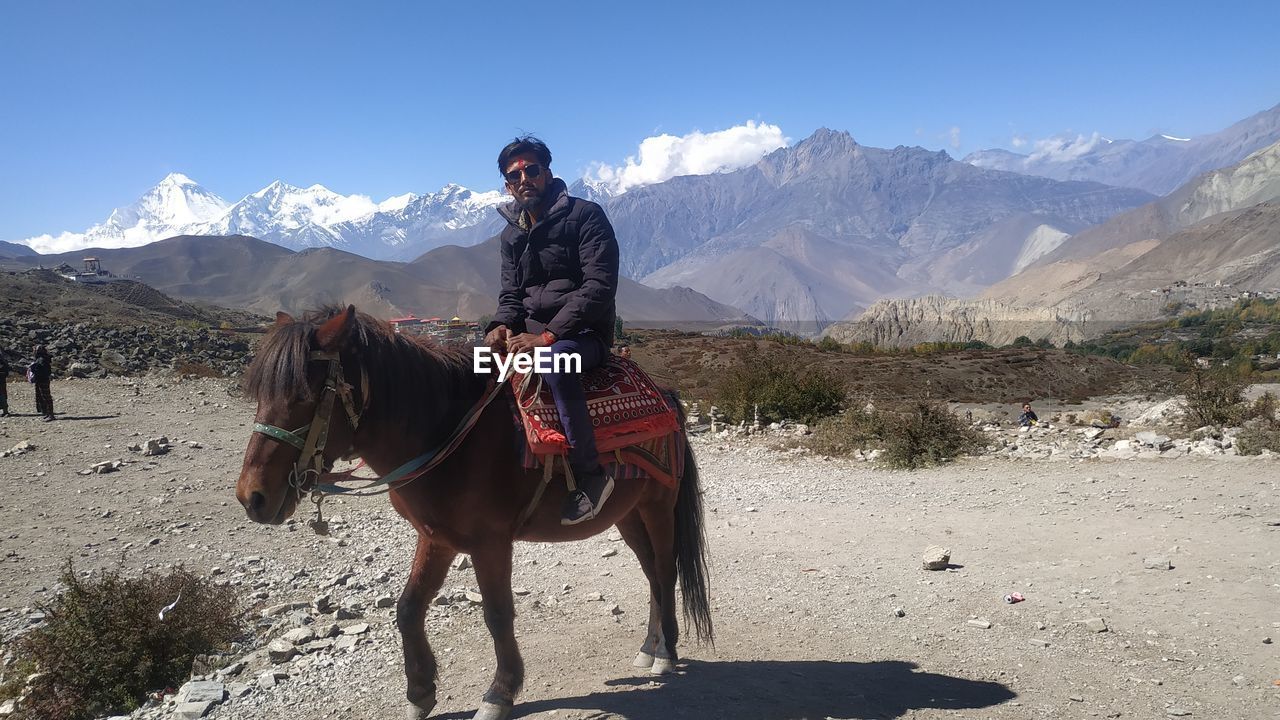 MAN RIDING HORSE ON MOUNTAIN