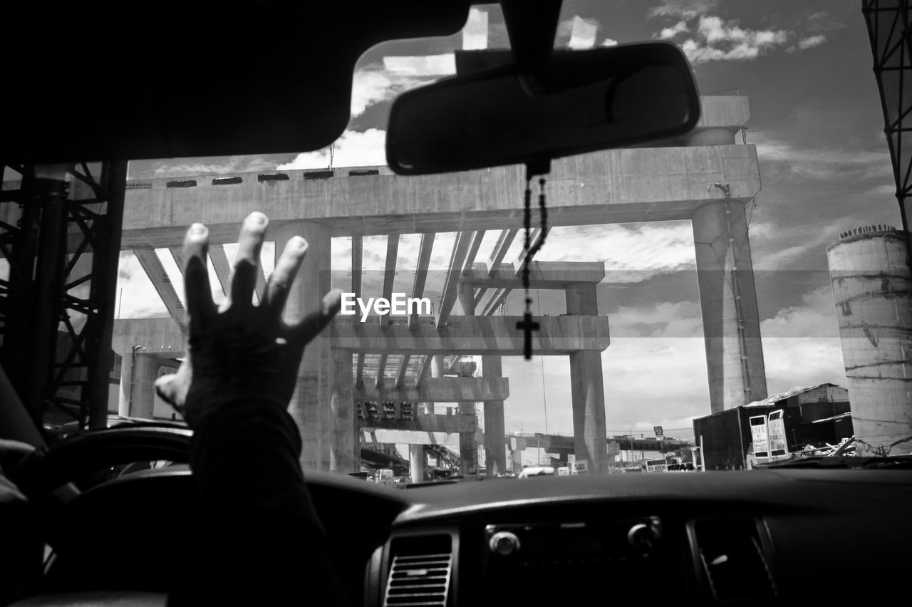 Cropped image of hand raised while driving car