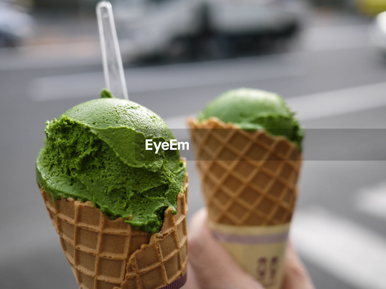 CLOSE-UP OF HAND HOLDING ICE CREAM CONE ON LEAF