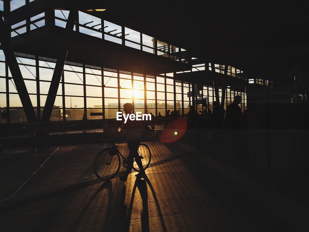 People at footbridge against sky during sunset