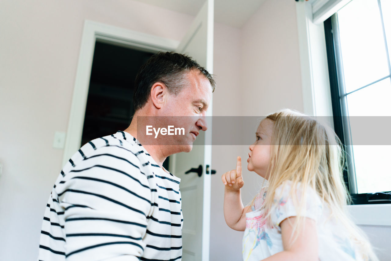 Side view of a toddler motioning for her dad to be quiet