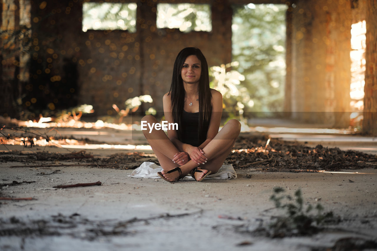 Portrait of young woman sitting in abandoned building