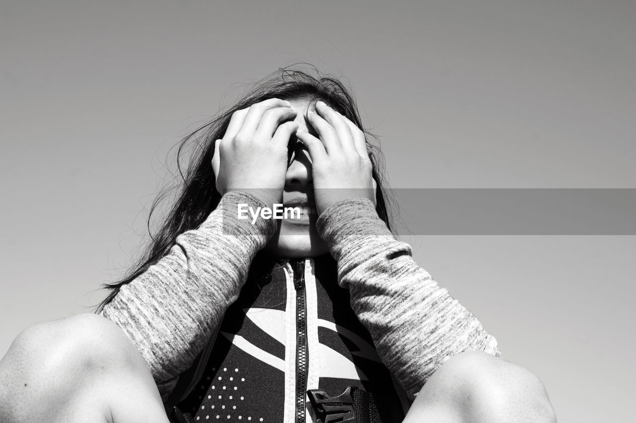 Low angle view of woman with hands over face