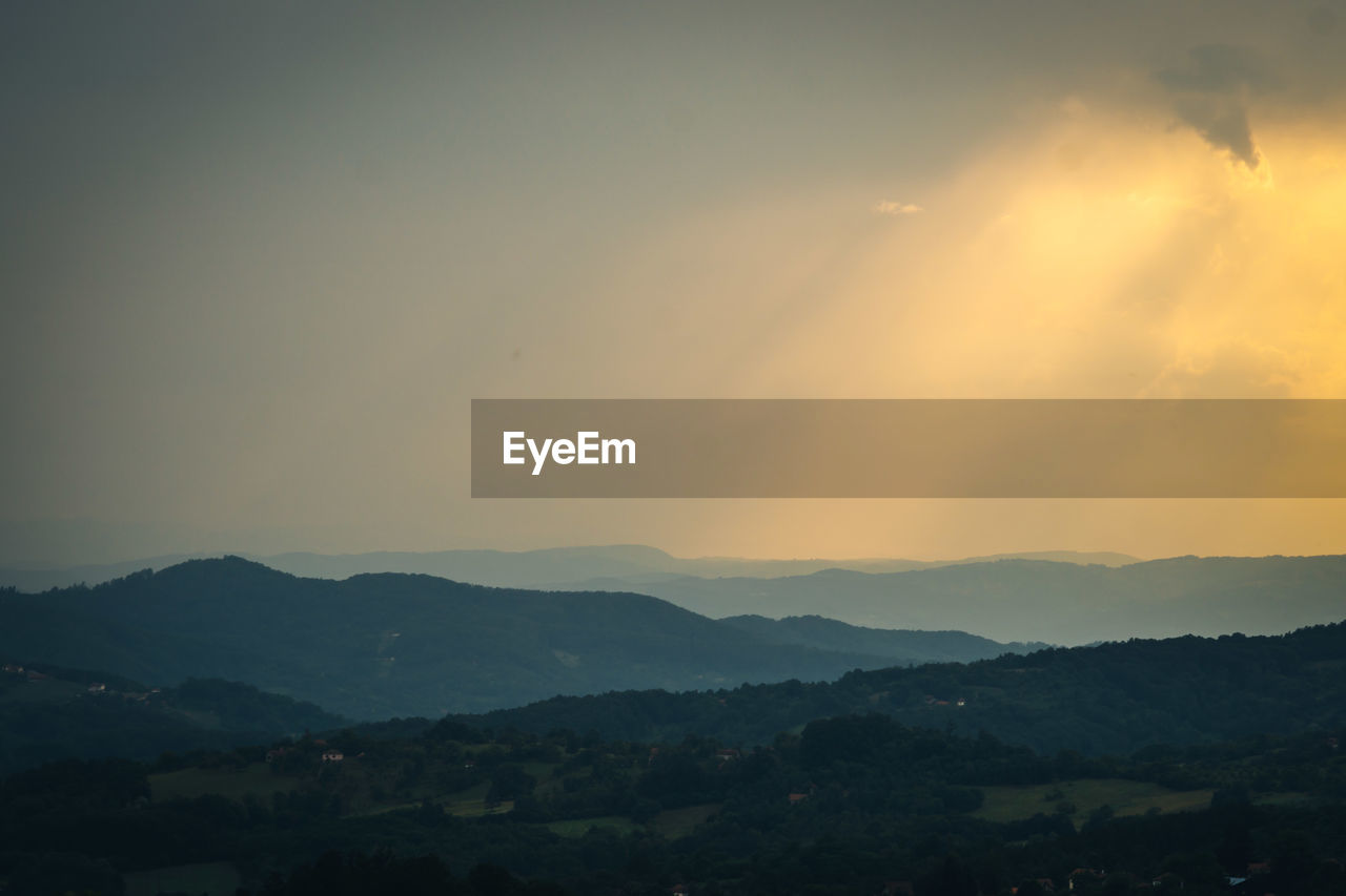 SCENIC VIEW OF SILHOUETTE MOUNTAINS AGAINST ORANGE SKY