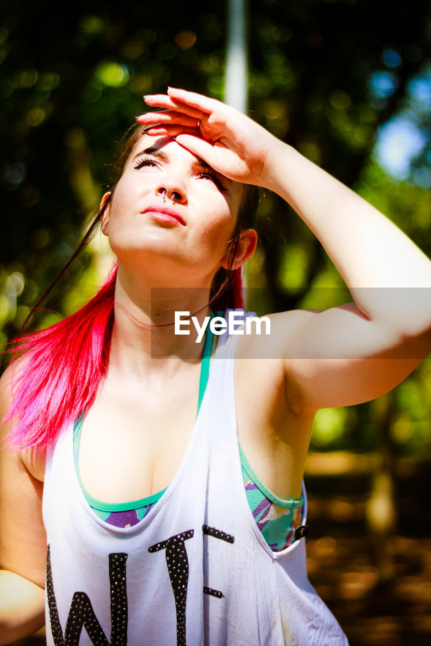 Young woman shielding eyes at park