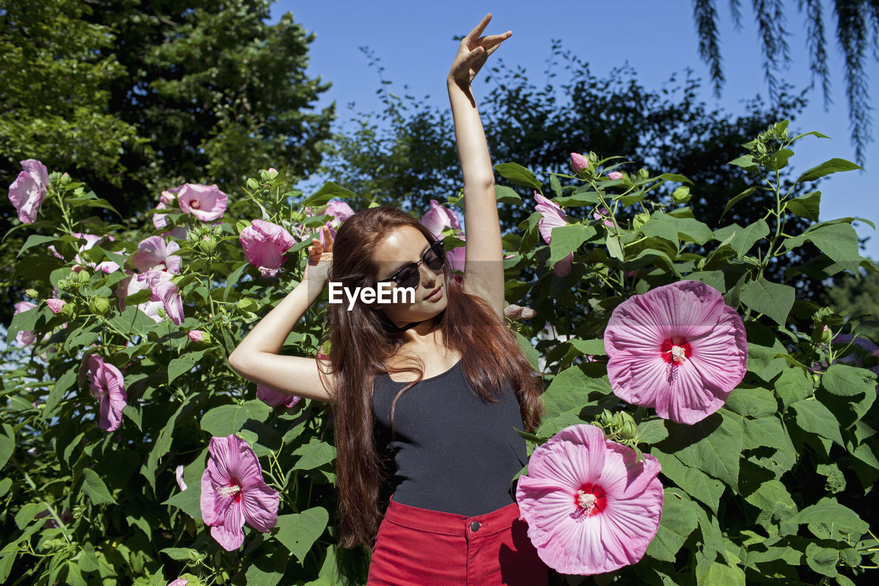 A young woman posing in front of a bush