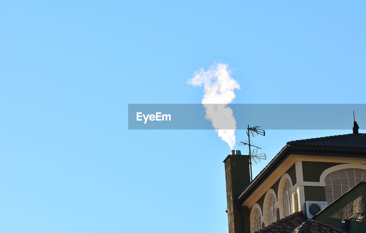 LOW ANGLE VIEW OF SMOKE EMITTING FROM CHIMNEY AGAINST BLUE SKY
