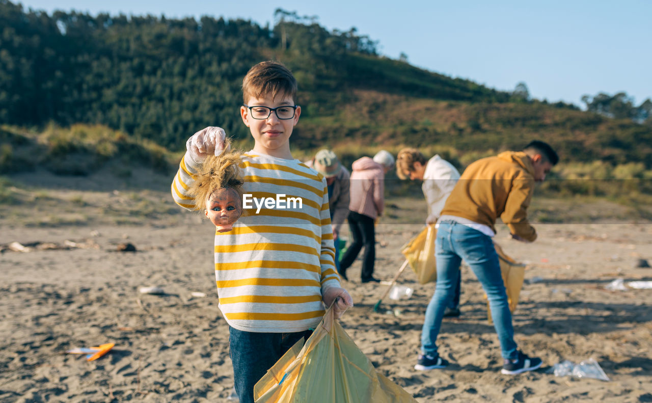 Boy showing broken doll while cleaning beach