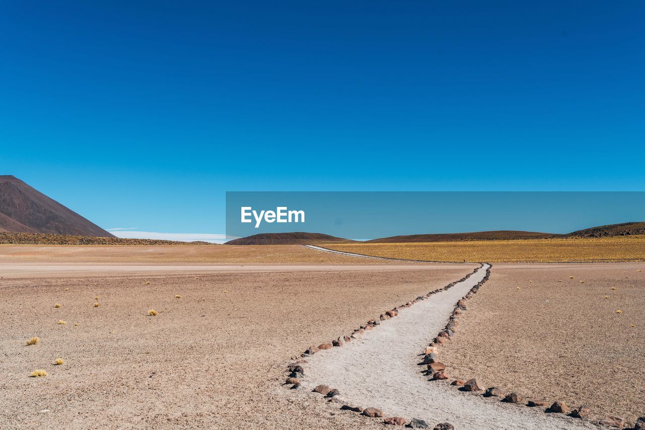 Scenic view of desert against clear blue sky