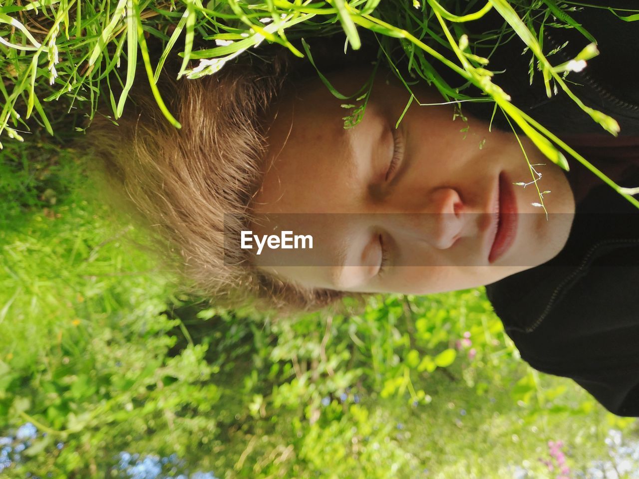 Close-up of young man sleeping on grassy field