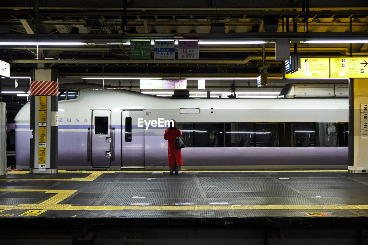 Rear view of woman standing at railroad station platform