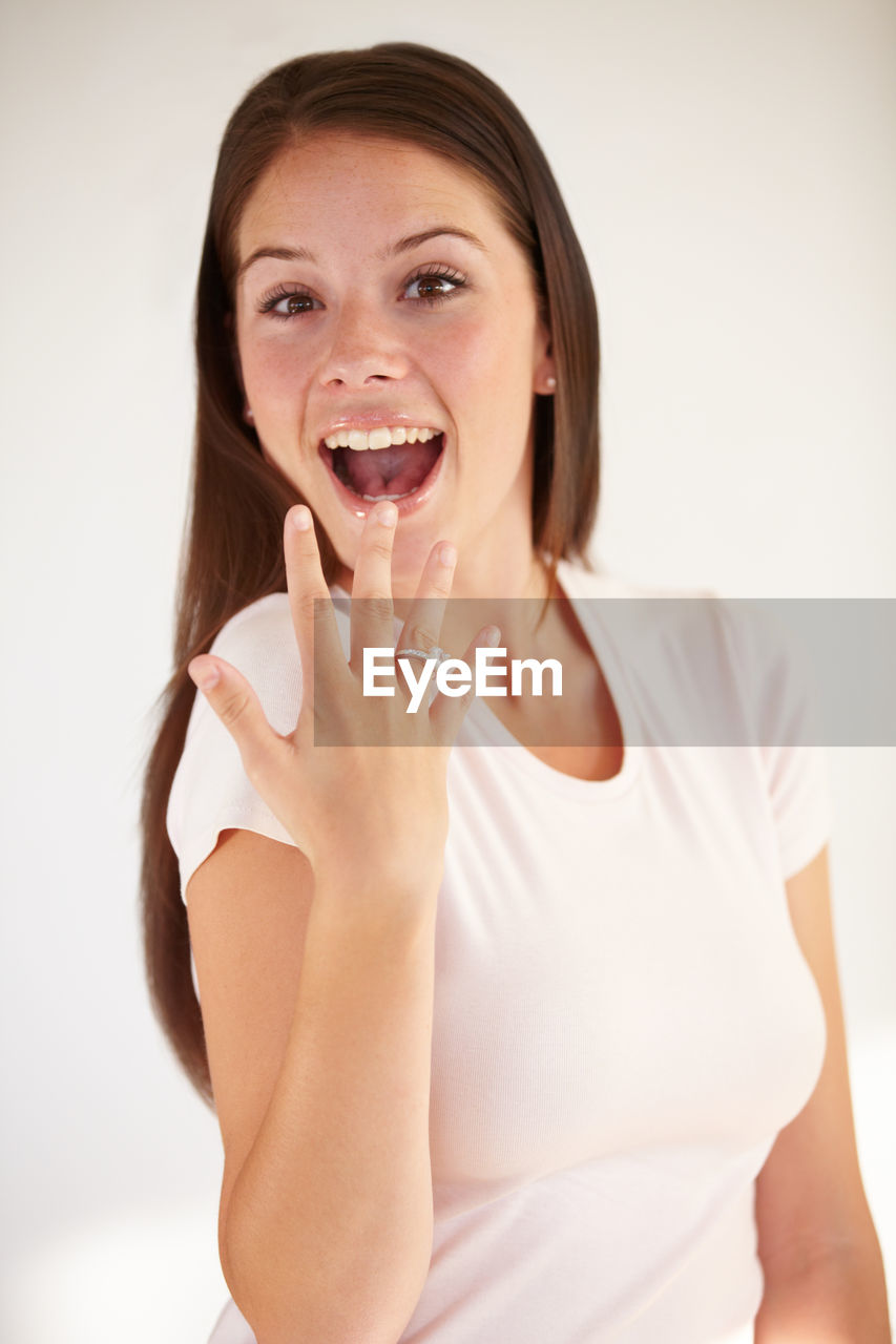 women, one person, adult, portrait, indoors, studio shot, emotion, young adult, happiness, finger, hand, looking at camera, smiling, brown hair, female, white background, mouth open, human face, cheerful, waist up, human mouth, positive emotion, nose, skin, limb, person, front view, hairstyle, lifestyles, relaxation, human leg, casual clothing, facial expression, human head, photo shoot, enjoyment, long hair, cut out, fun, arm, laughing, holding