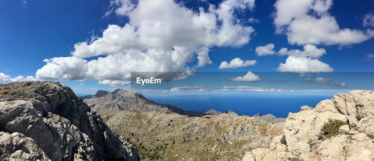 Panoramic view of rocky mountains against blue sky