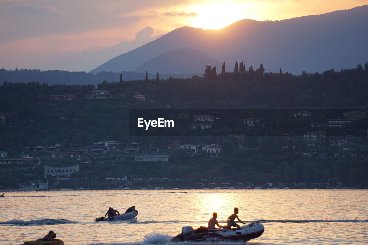 PEOPLE ON SEA AGAINST SKY DURING SUNSET