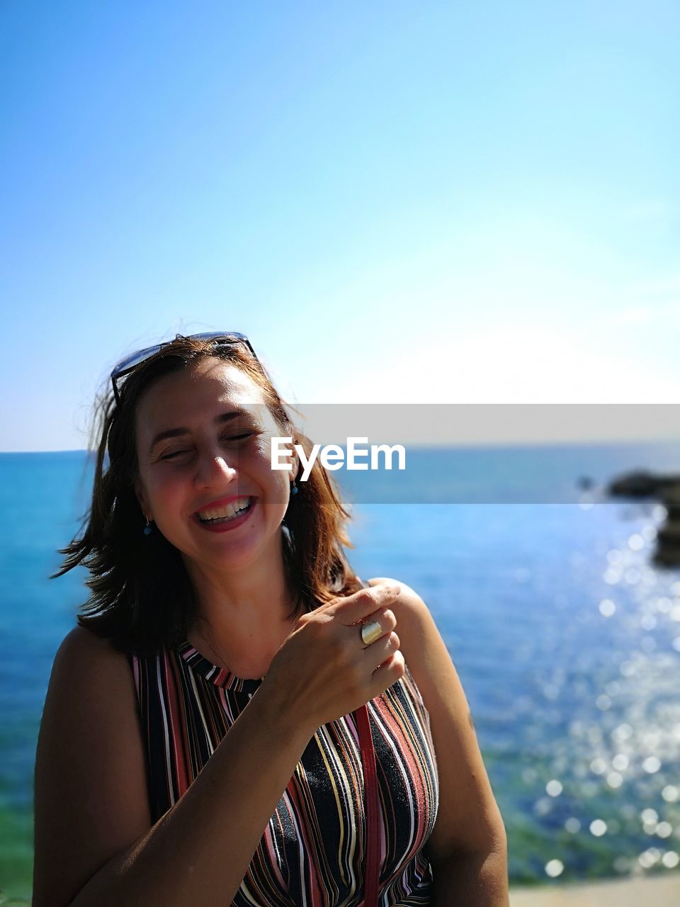 Portrait of smiling young woman against sea