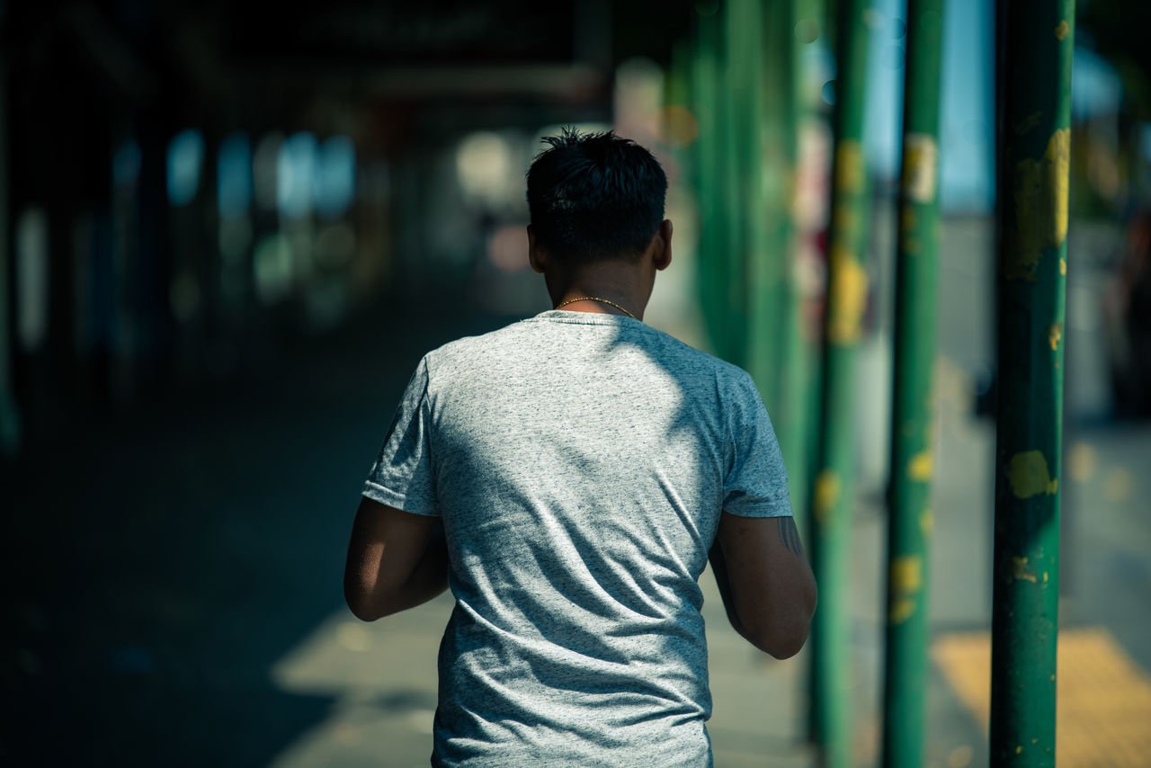 REAR VIEW OF MAN WITH UMBRELLA WALKING OUTDOORS