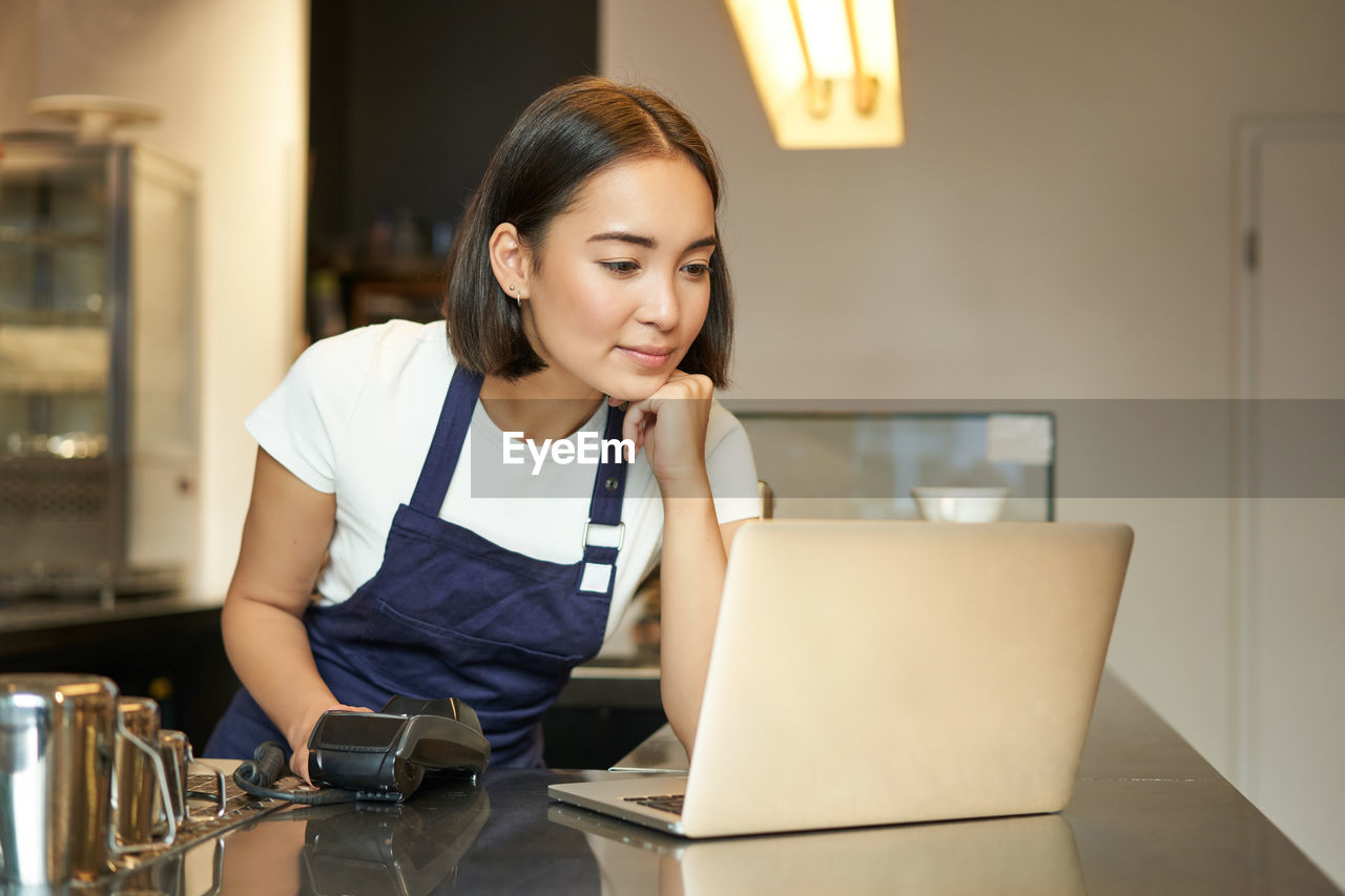 side view of young woman using laptop while sitting at home