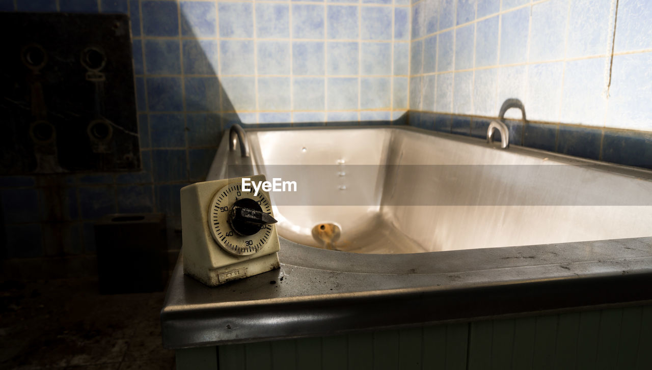 Vintage timer on bathtub in abandoned bathroom