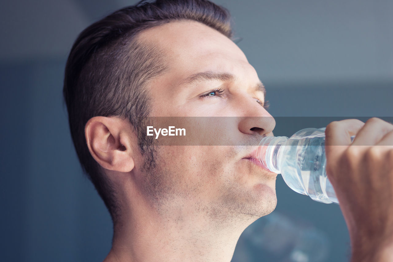 CLOSE-UP PORTRAIT OF YOUNG MAN DRINKING WATER