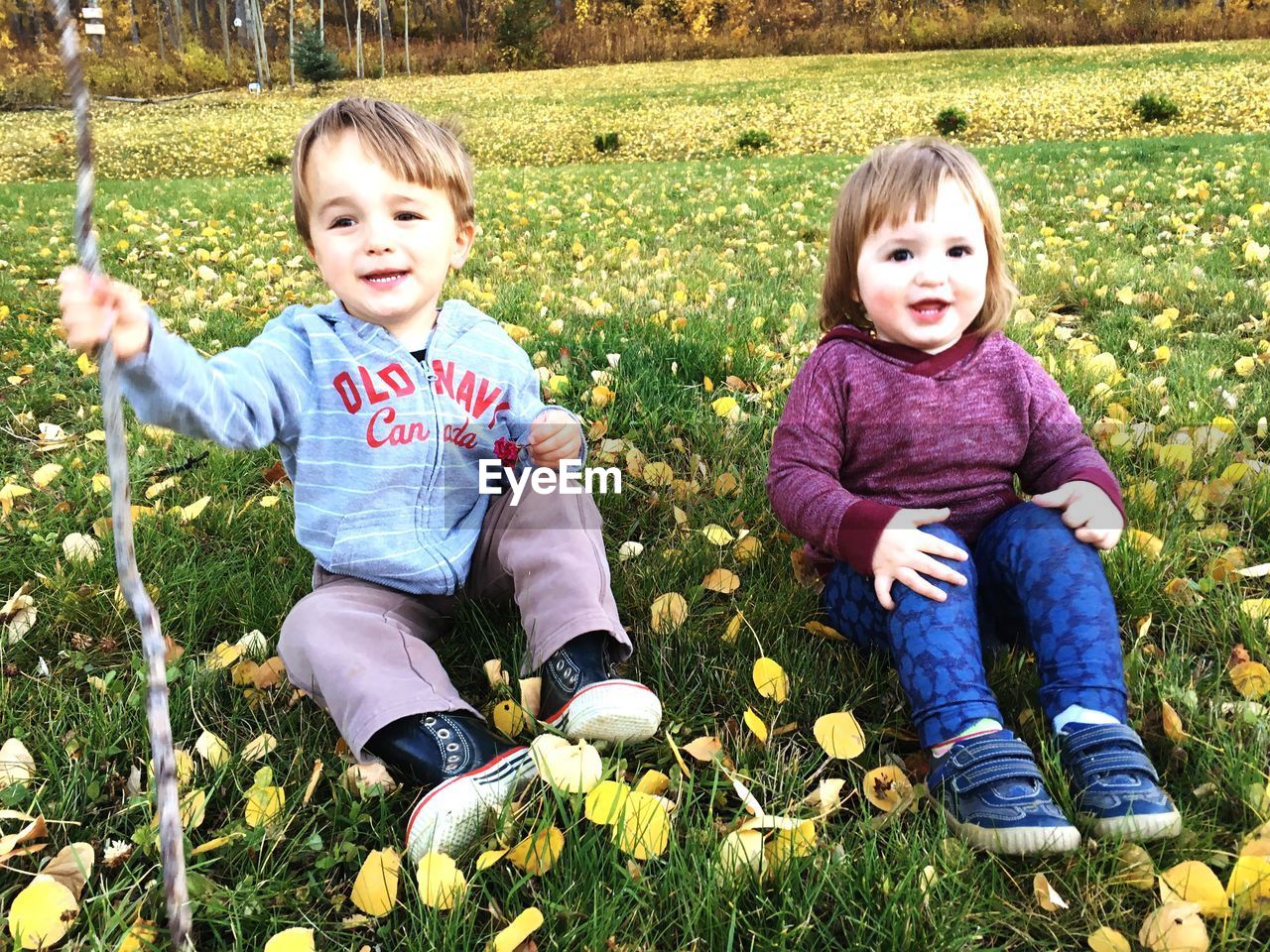 PORTRAIT OF HAPPY GIRL STANDING ON GRASSY FIELD