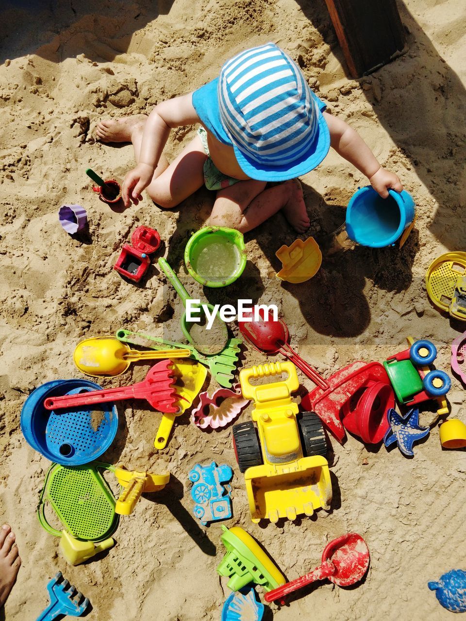 Directly above shot of boy playing with toys on sand at beach