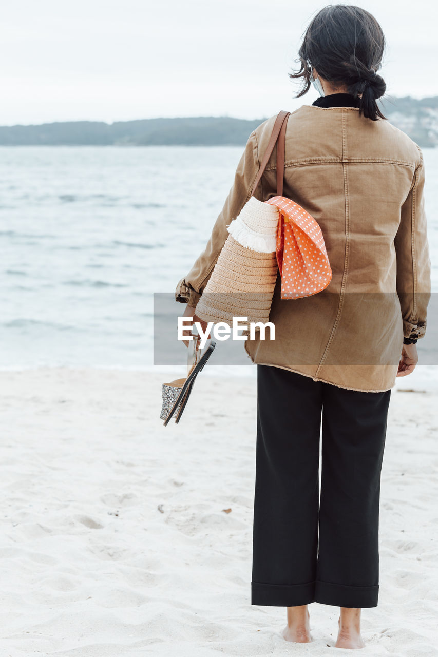 rear view of young woman standing at beach