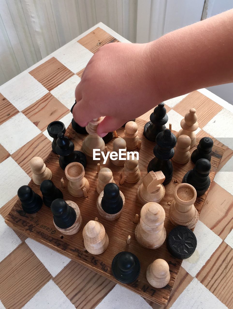 Cropped hand of person picking chess pieces on table