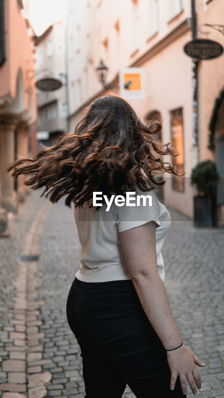 MIDSECTION OF WOMAN STANDING BY STREET
