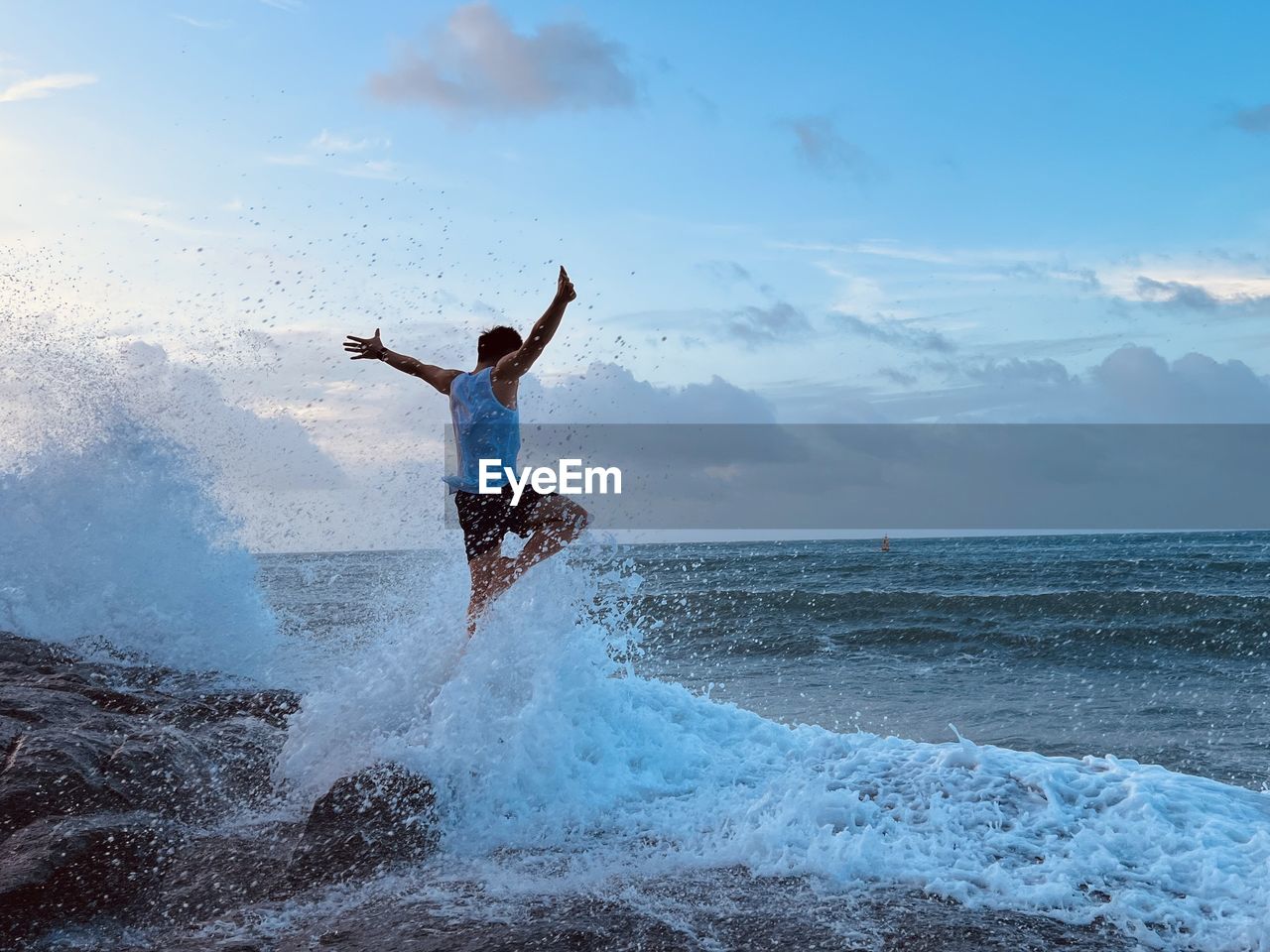 Rear view of man surfing in sea against sky