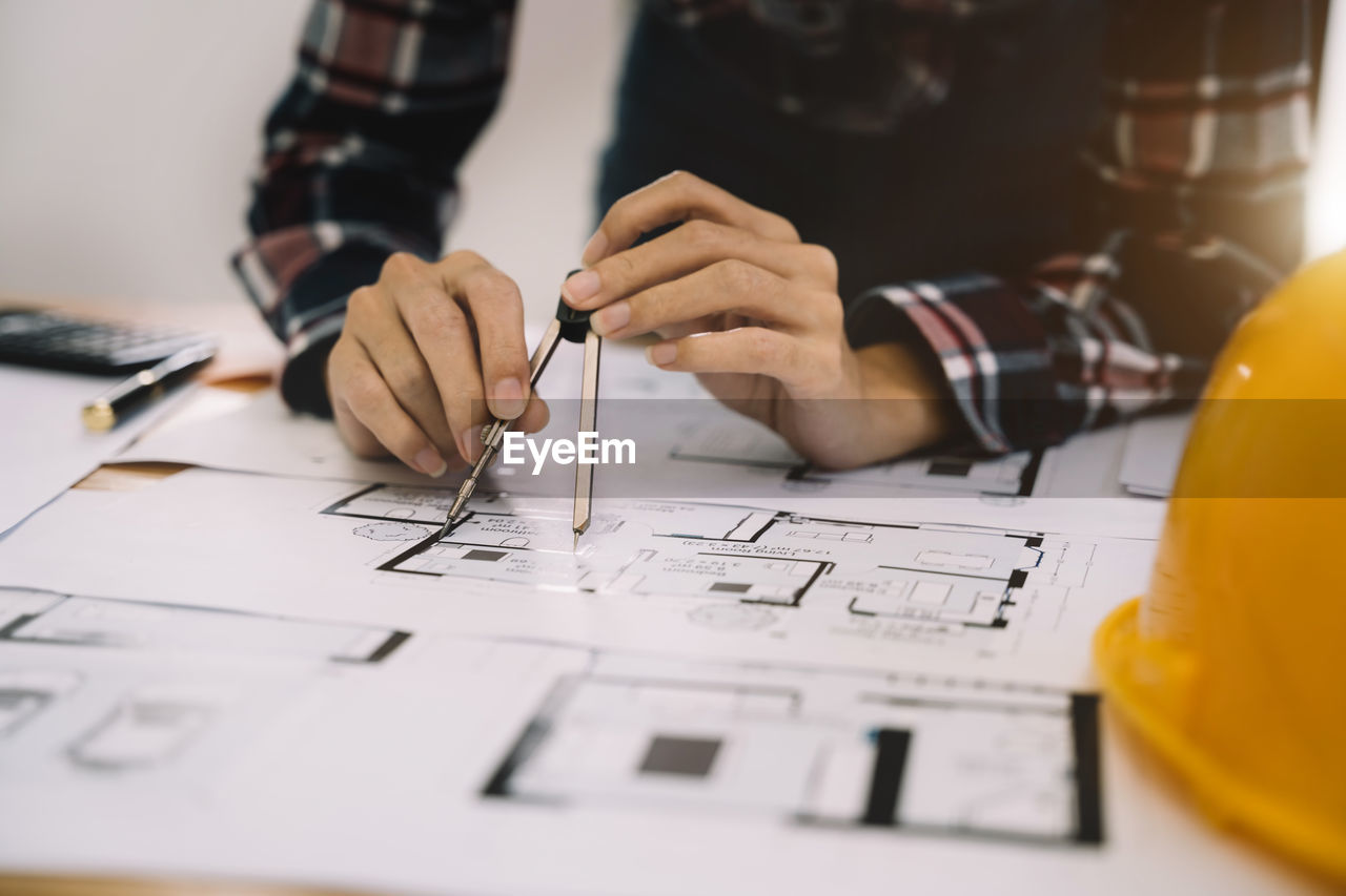 midsection of man working on blueprint