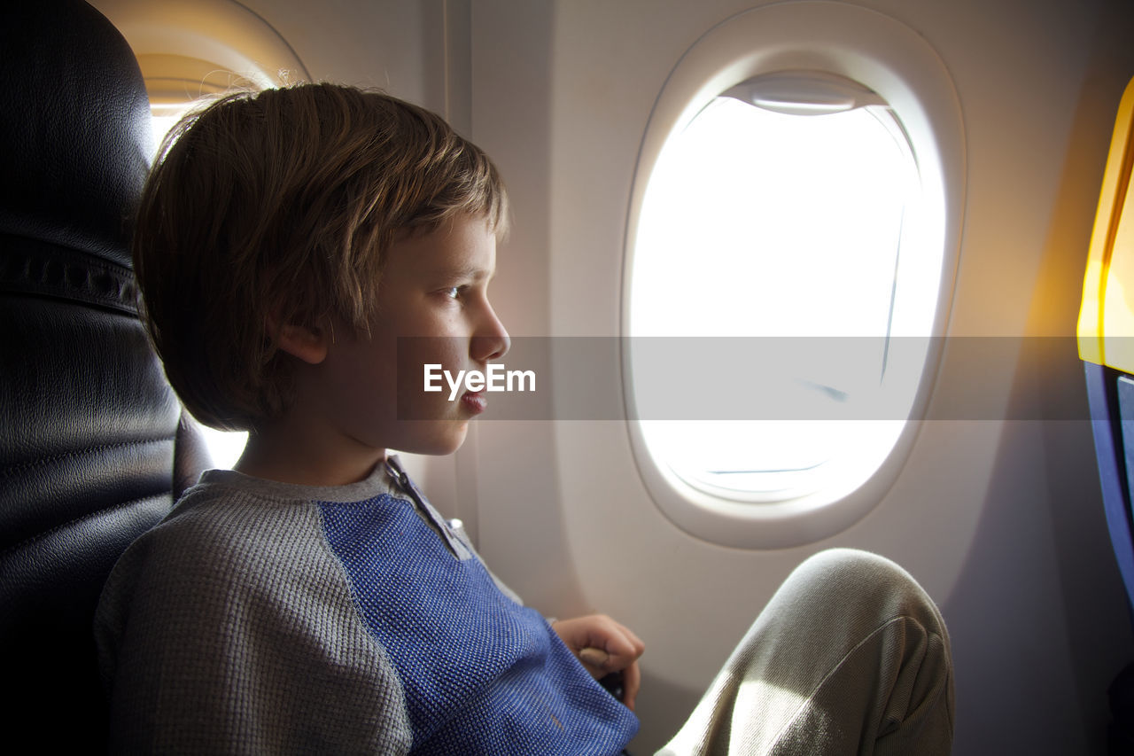 Boy looking through airplane window
